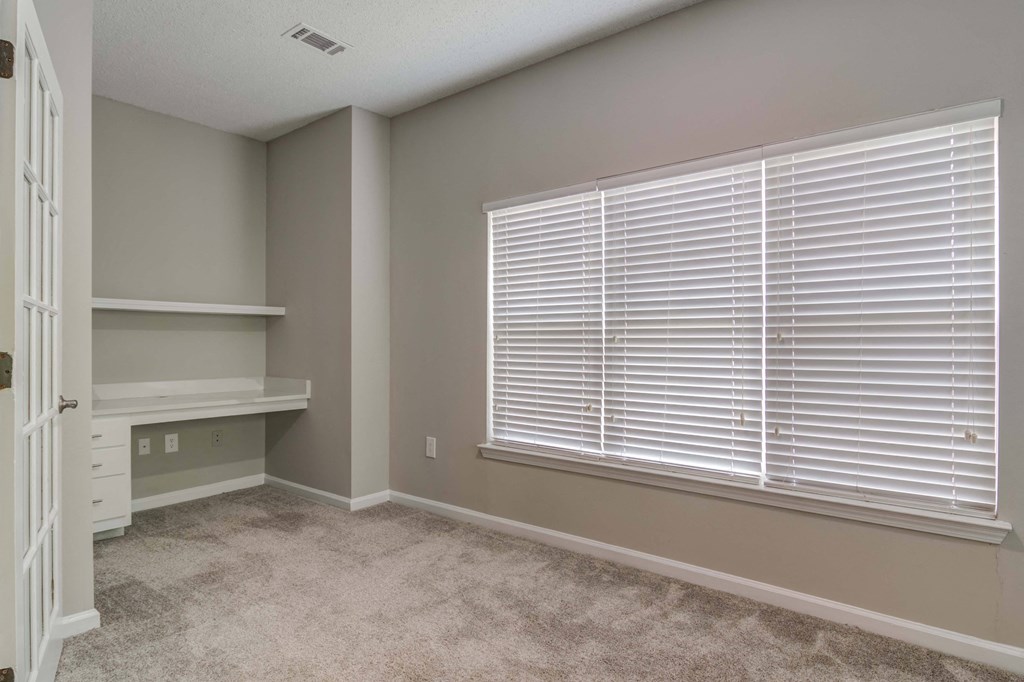 Woodstock, GA Apartments – Lea Woodstock – bedroom with plush carpeting, large windows, and built in desk.