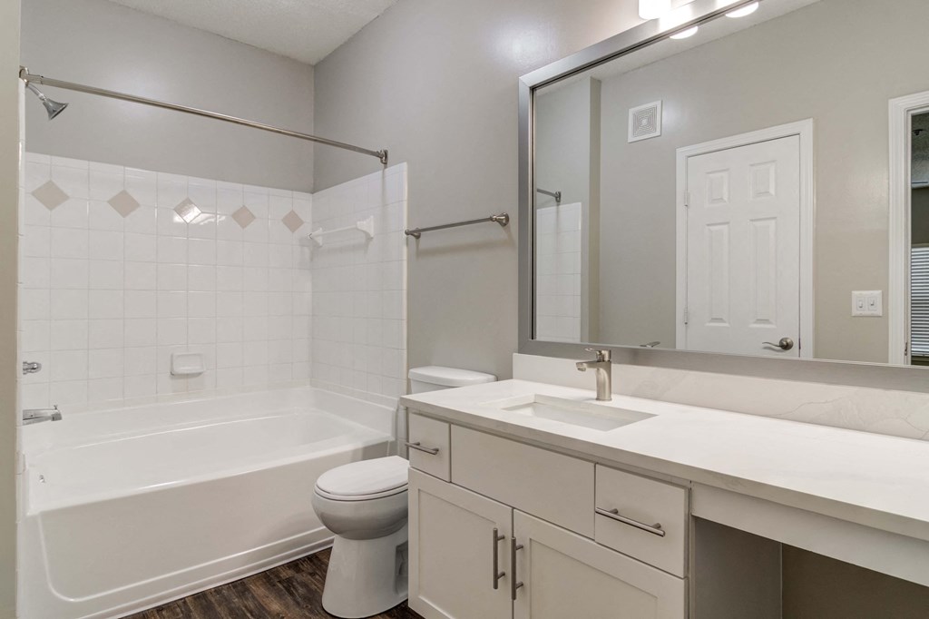 Pet-Friendly Apartments in Woodstock, GA – Lea Woodstock – bathroom with white cabinets, quartz counter tops, a toilet and a tub/shower