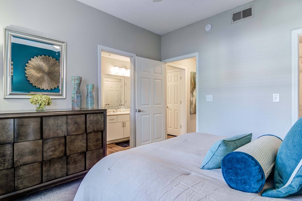 Pet-Friendly Apartments in Woodstock, GA – Lea Woodstock – bedroom with bed and dresser with view of bathroom and hallway