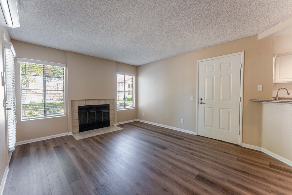 an empty living room with wood flooring and a fireplace