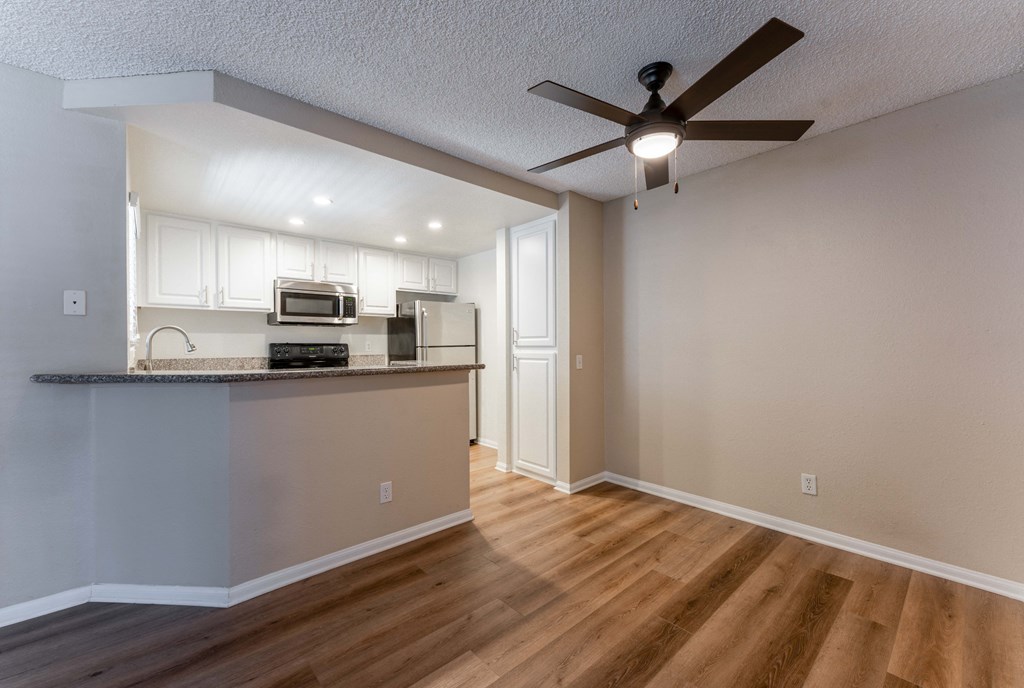 an empty living room and kitchen with a ceiling fan