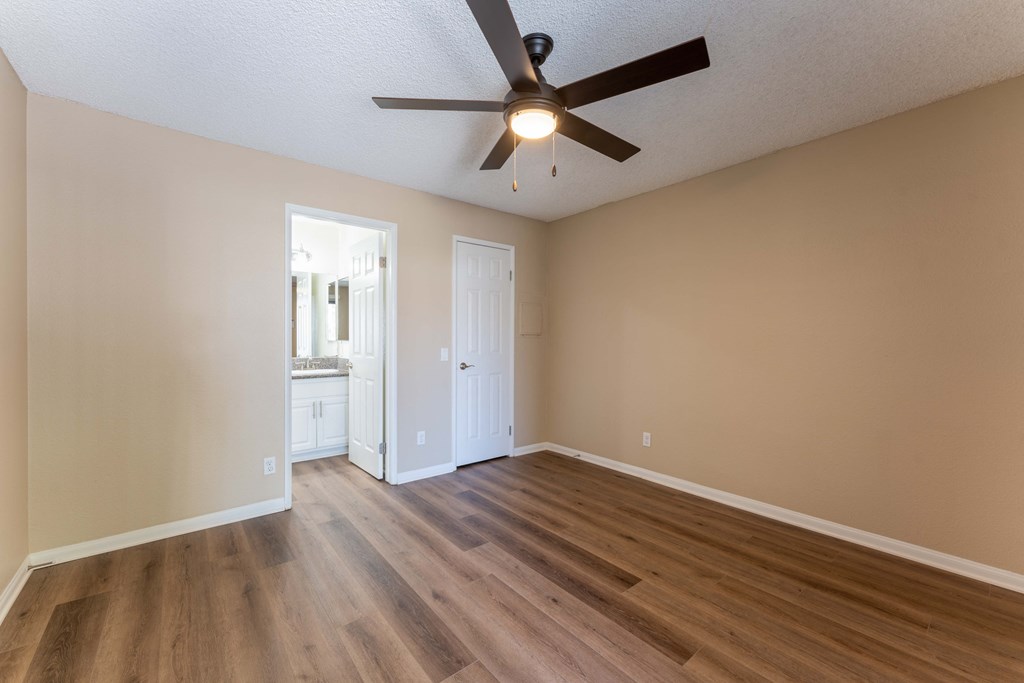 an empty living room with wooden floors and a ceiling fan