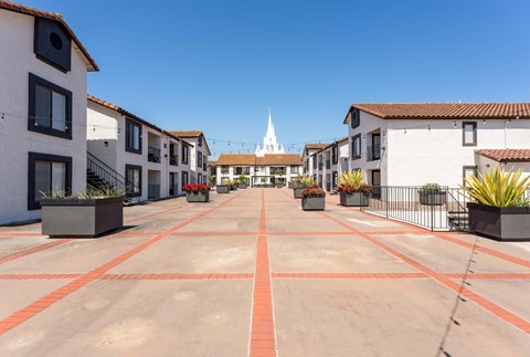 an empty parking lot with buildings and a church in the background