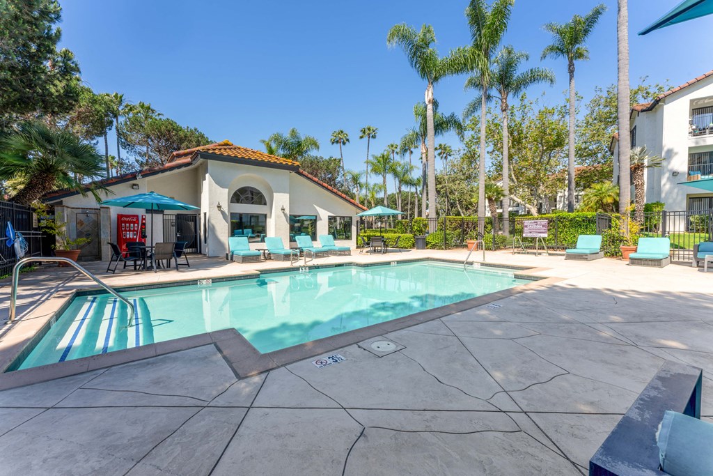 Apartments in La Jolla, CA for Rent - Mirada at La Jolla Colony - Swimming Pool with Lounge Chairs, Umbrellas, Tables with Chairs, and Beautiful Landscaping