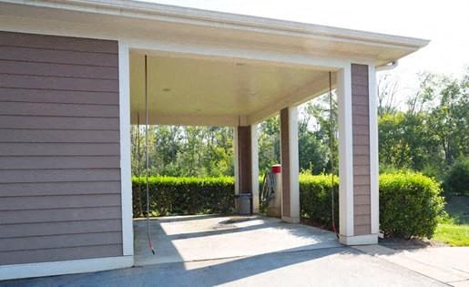 covered car wash area with ceiling-mounted water hoses and car vacuum station