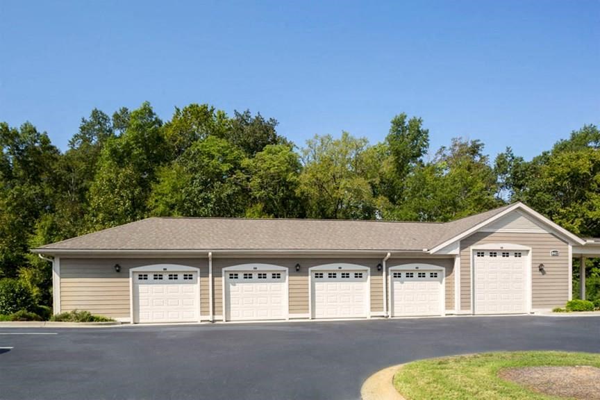building with five covered and enclosed parking garages with tan siding and white garage doors