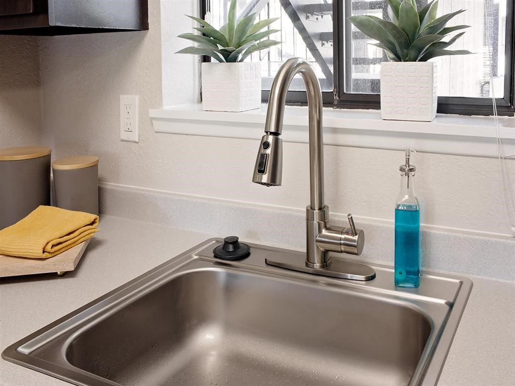a kitchen sink with a bottle of blue soap sitting next to a window