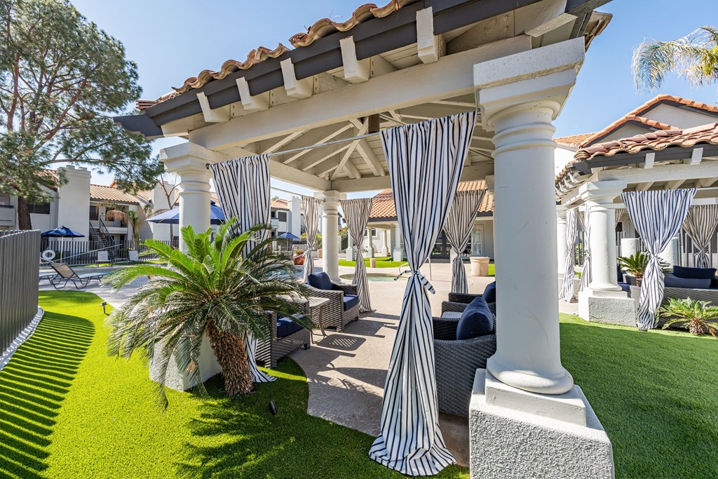 a patio with blue and white striped curtains and lawn furniture