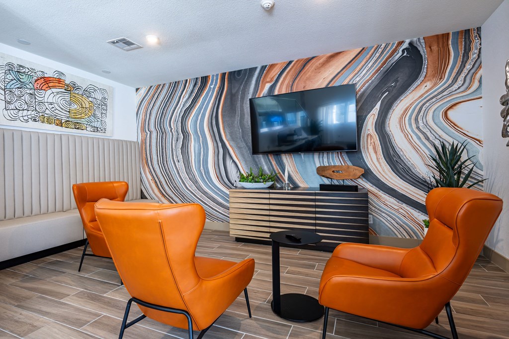 the lobby of a hotel with orange chairs and a television