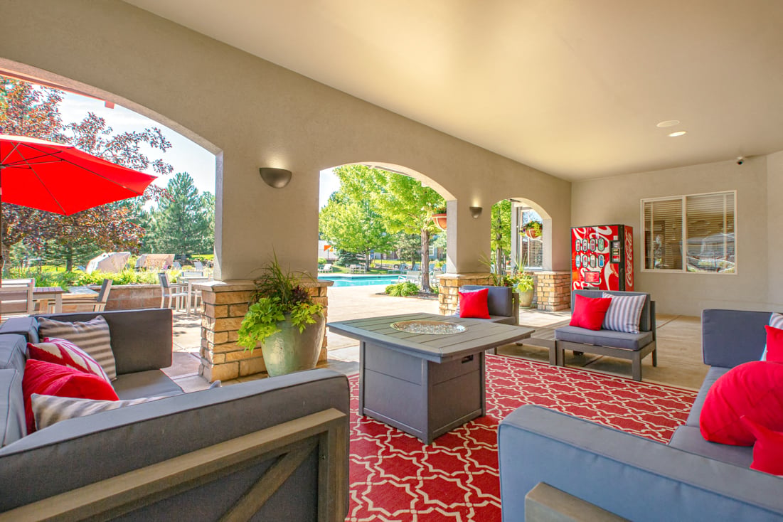A living room with a grey couch and red pillows.