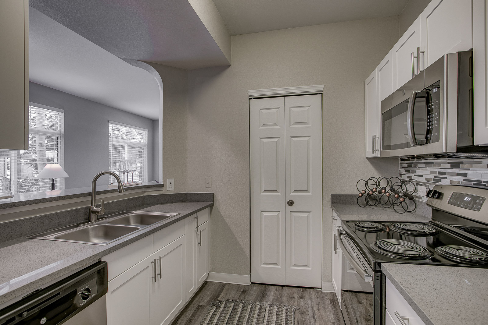 A kitchen with white cabinets and a white door.