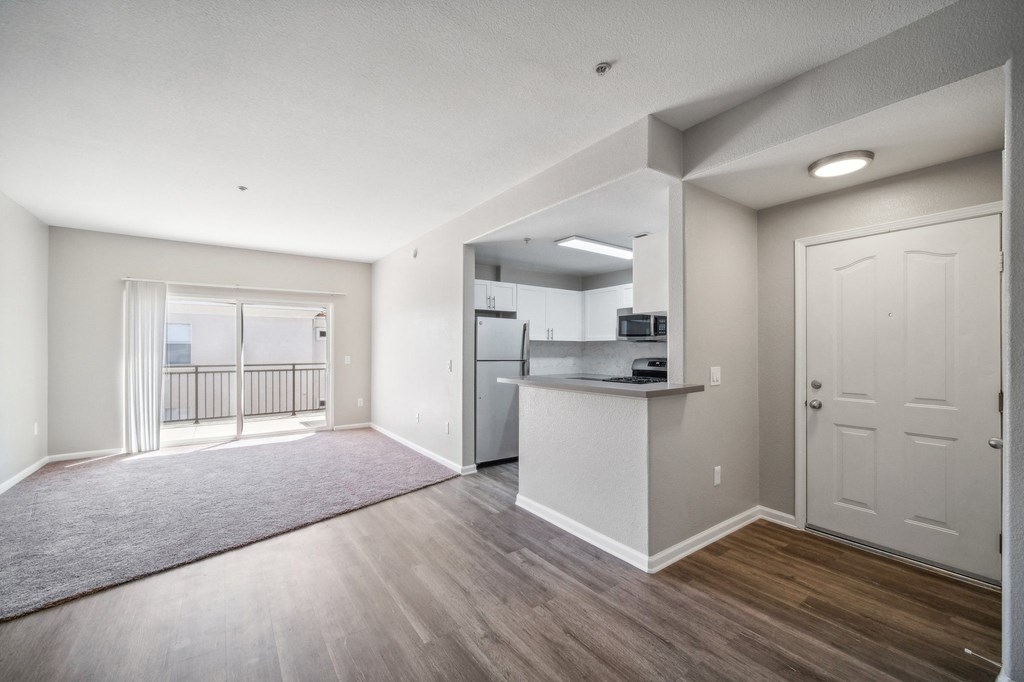 an empty living room and kitchen with a door to a balcony