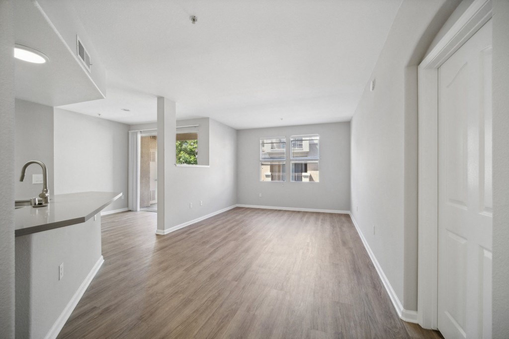 an empty living room and kitchen with white walls and wood floors