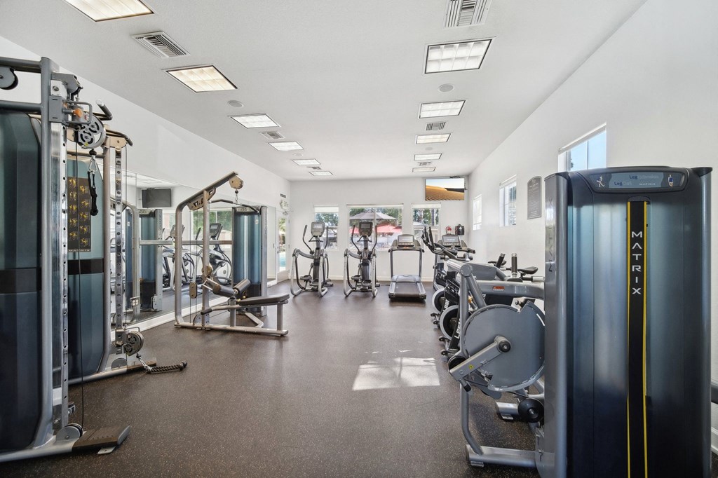 a gym with cardio equipment and weights on the floor