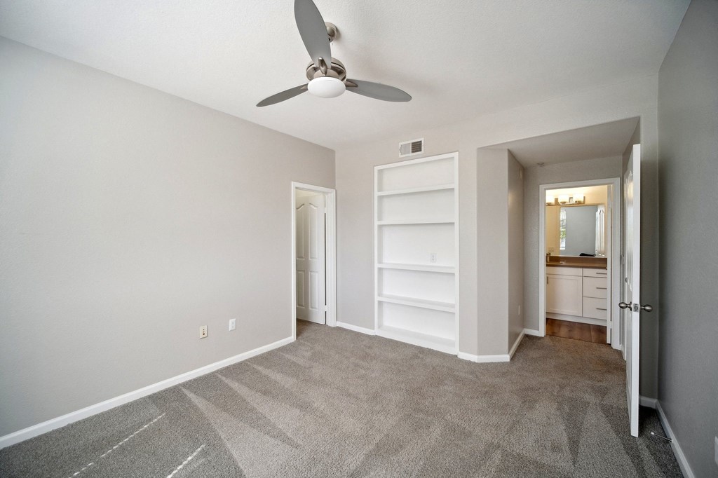 an empty living room with a ceiling fan and a closet