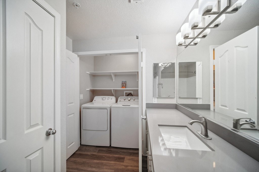 a white laundry room with a sink and a washer and dryer in it
