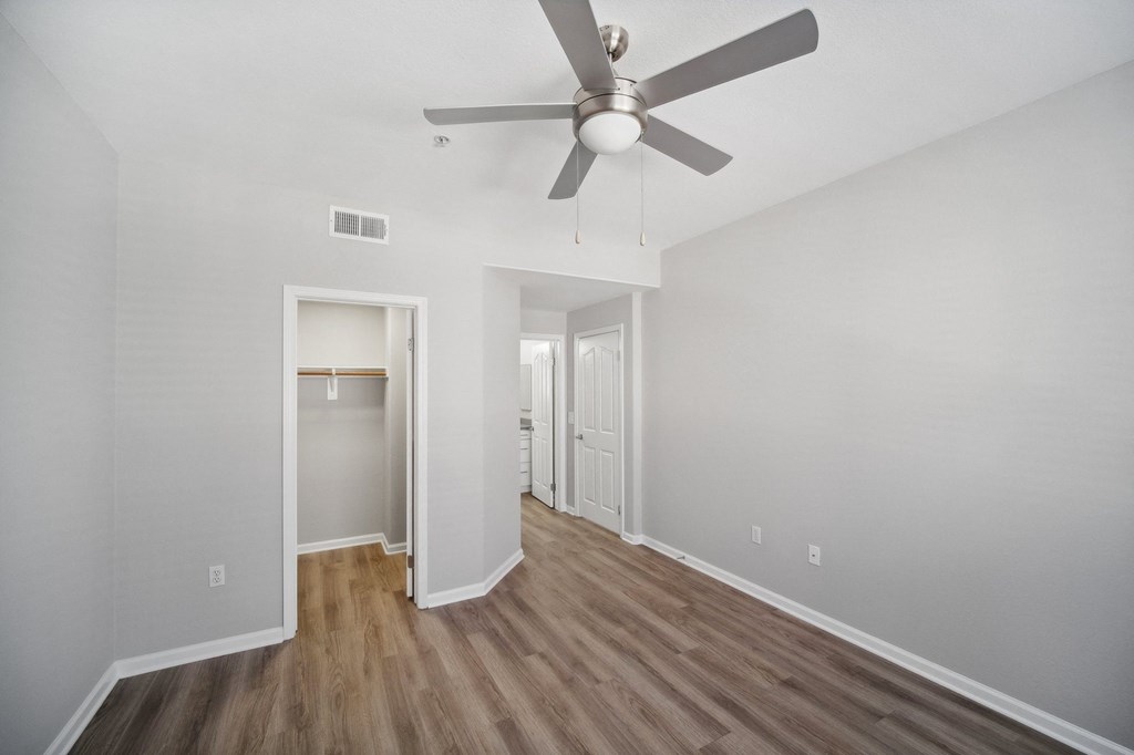 the living room of an empty apartment with a ceiling fan