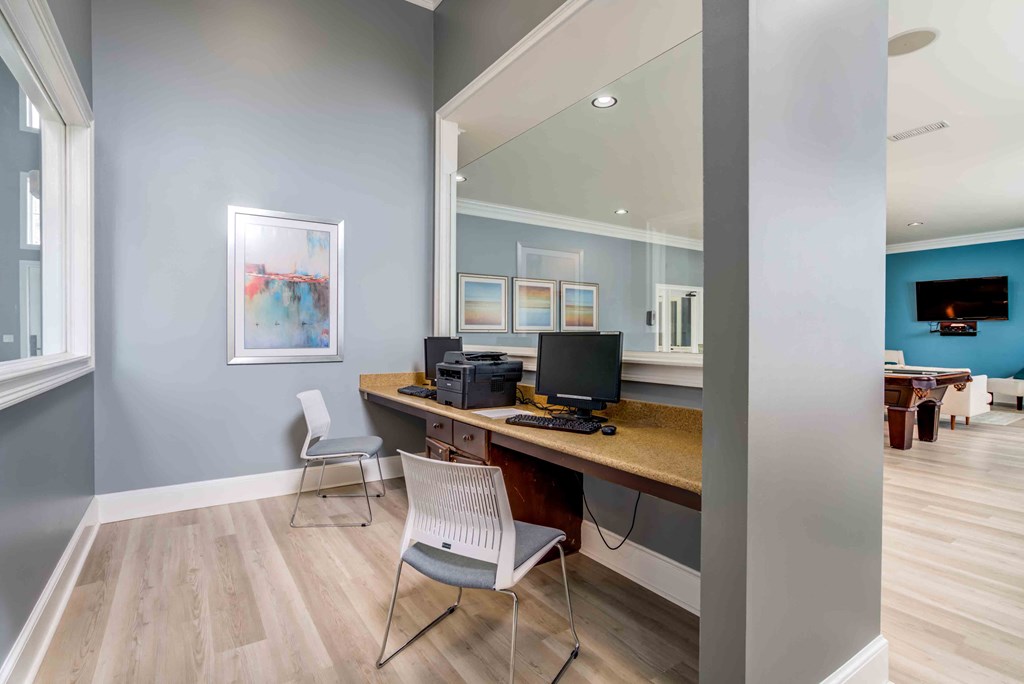 a room with a desk with two chairs and a computer