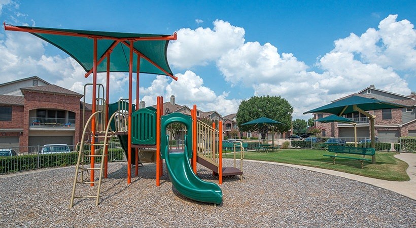 a playground with a swing set and slides in a park
