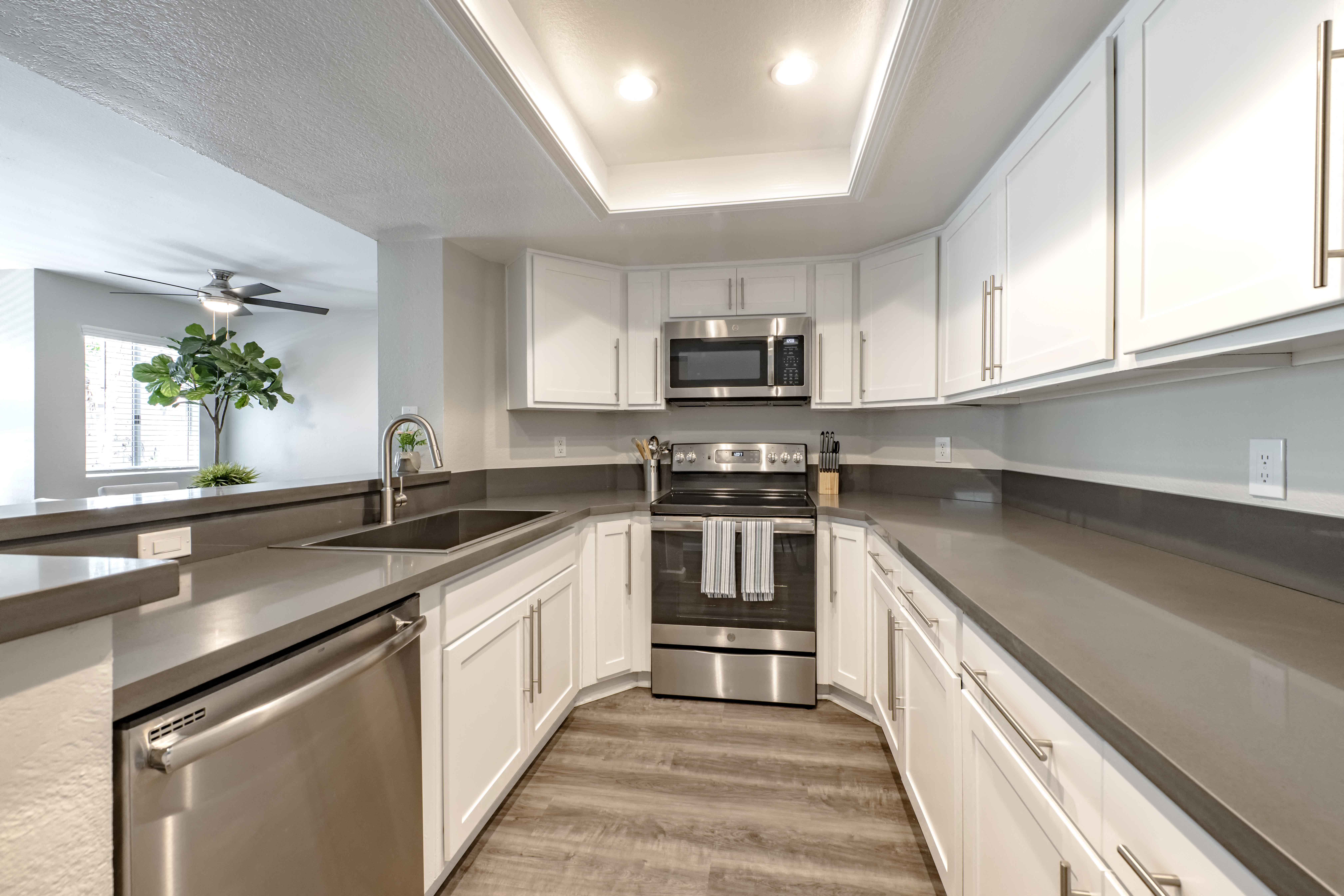 San Clemente, CA Apartments - Rancho Del Mar - Kitchen with White Cabinets, Grey Countertops, Deep Basin Sink, and Stainless Steel Appliances.