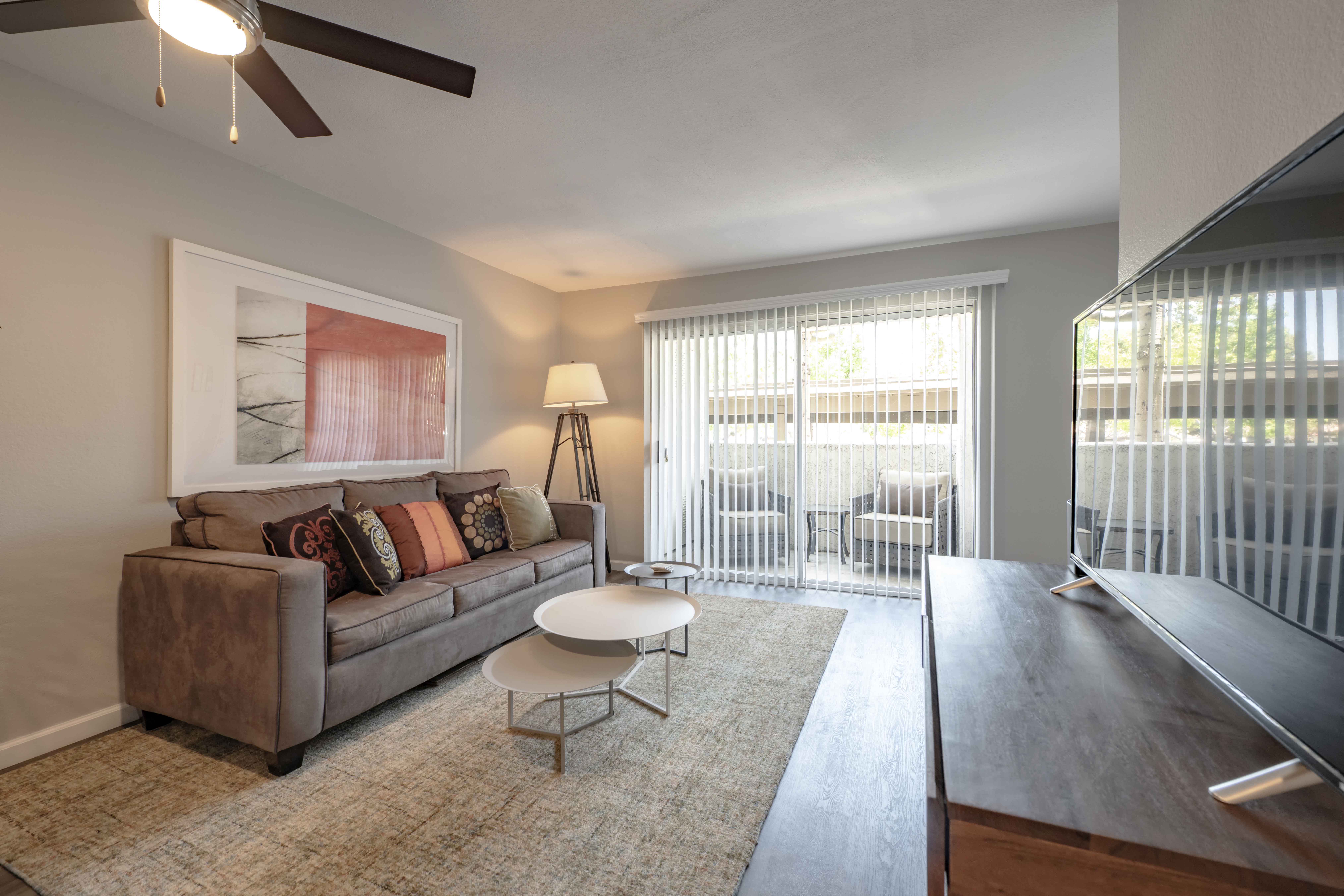 Apartments for Rent in San Clemente, CA - Rancho Del Mar - Furnished Living Room with Hardwood-Inspired Flooring, Stylish Decor, and a Sliding Glass Door to a Private Patio/Balcony