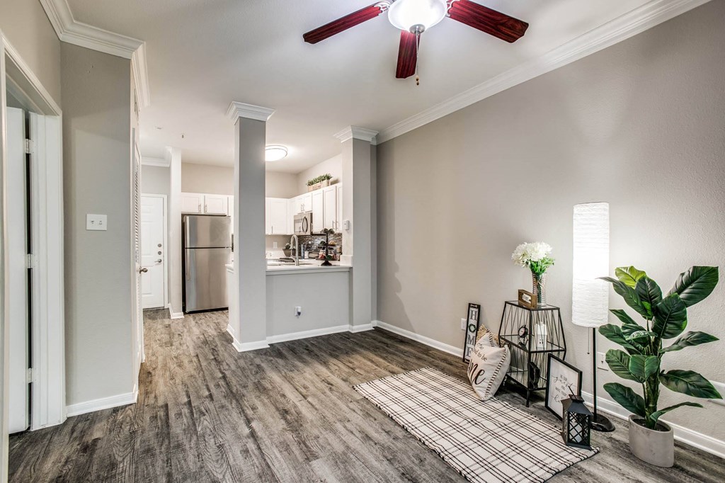an empty living room with a ceiling fan and a kitchen