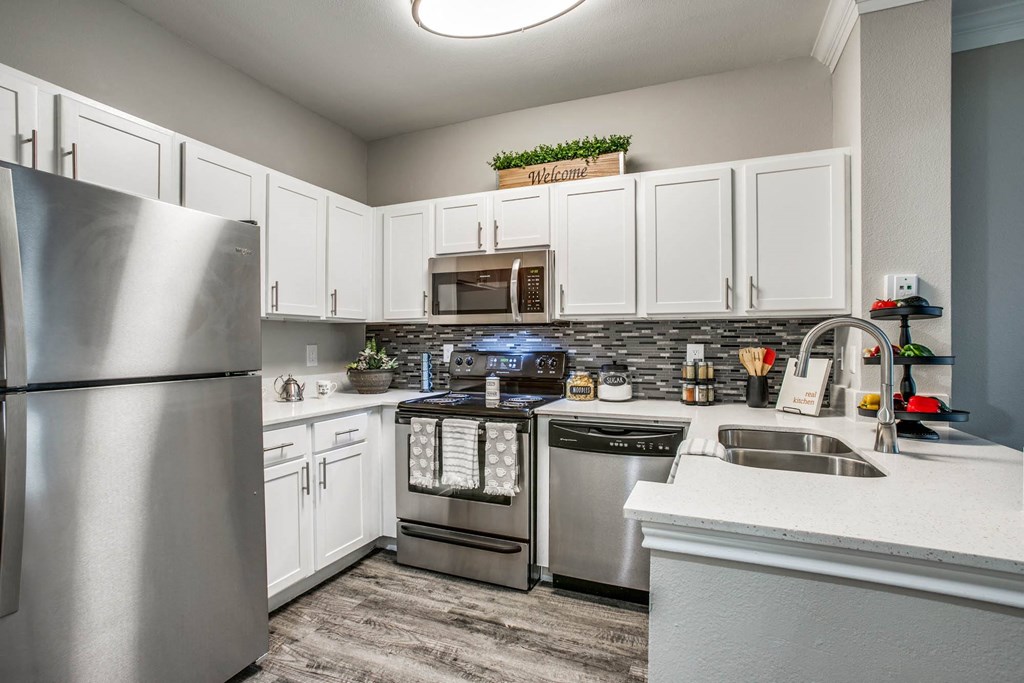 Apartments Houston, TX - Large Kitchen with Stainless Steel Appliances, White Cabinets, and Tiled Backsplash
