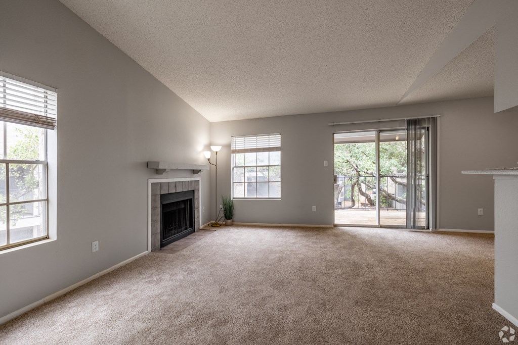 an empty living room with a fireplace and a sliding glass door