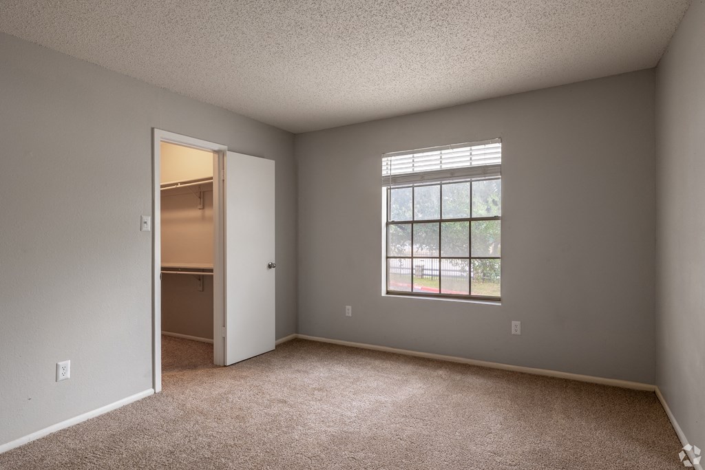 an empty living room with a window and a door to a kitchen