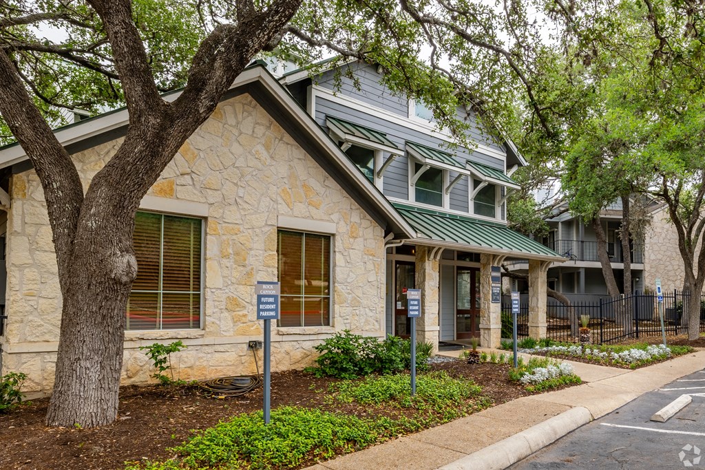 a stone building with trees and a sidewalk in front of it