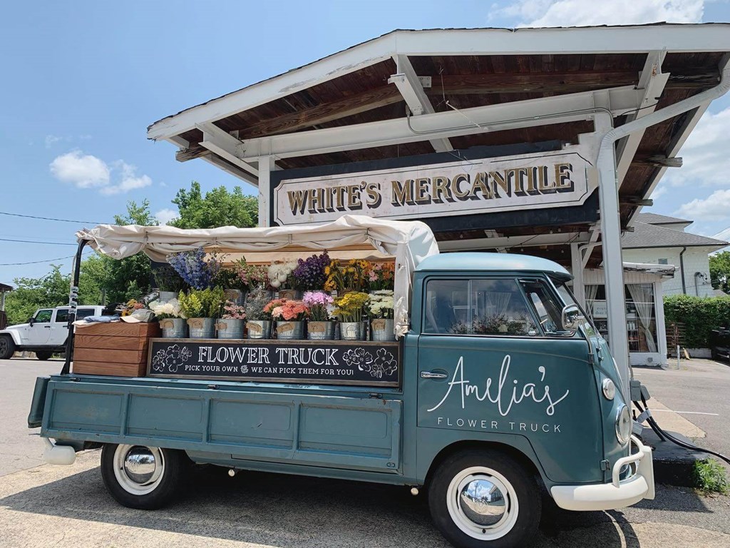an old blue truck parked in front of a flower truck