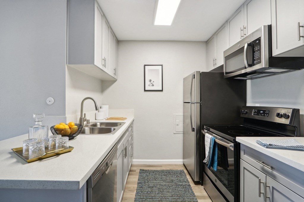 Apartments in Van Nuys, CA - San Regis - Bright Gourmet Kitchen with Stainless-Steel Appliances, Granite Counters, and Vinyl Plank Flooring