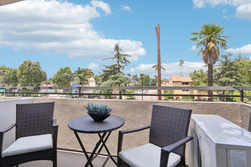 a patio with two chairs and a table on a balcony