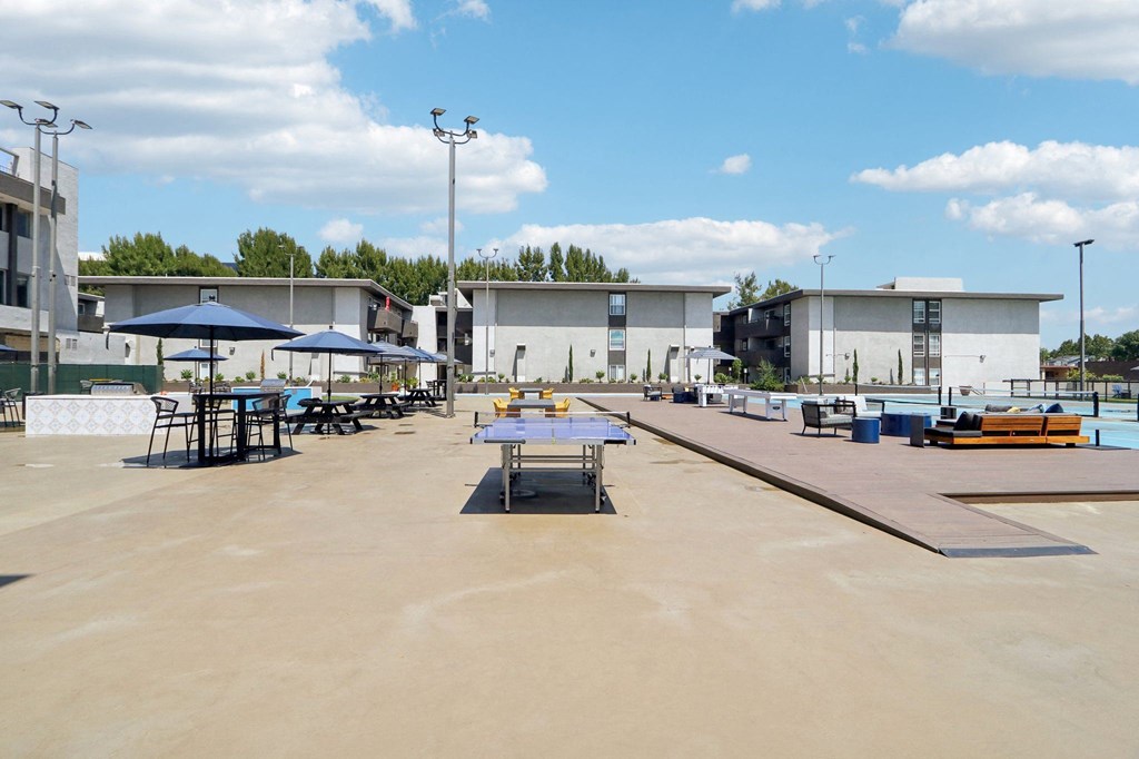 a large patio with tables and umbrellas and buildings in the background