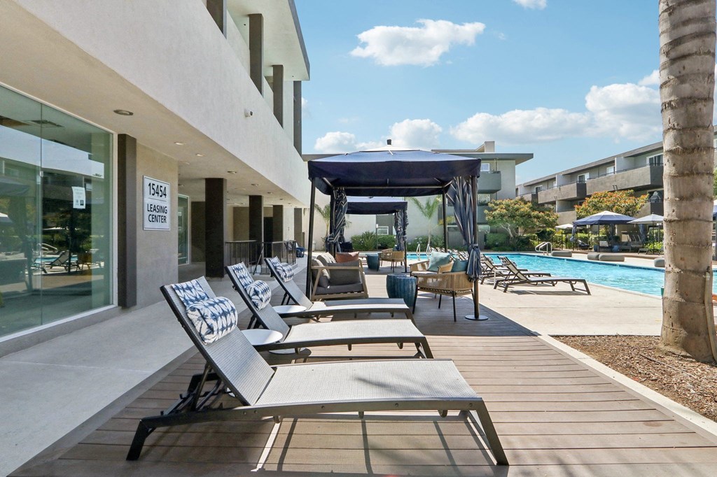 a group of lounge chairs on a patio next to a swimming pool