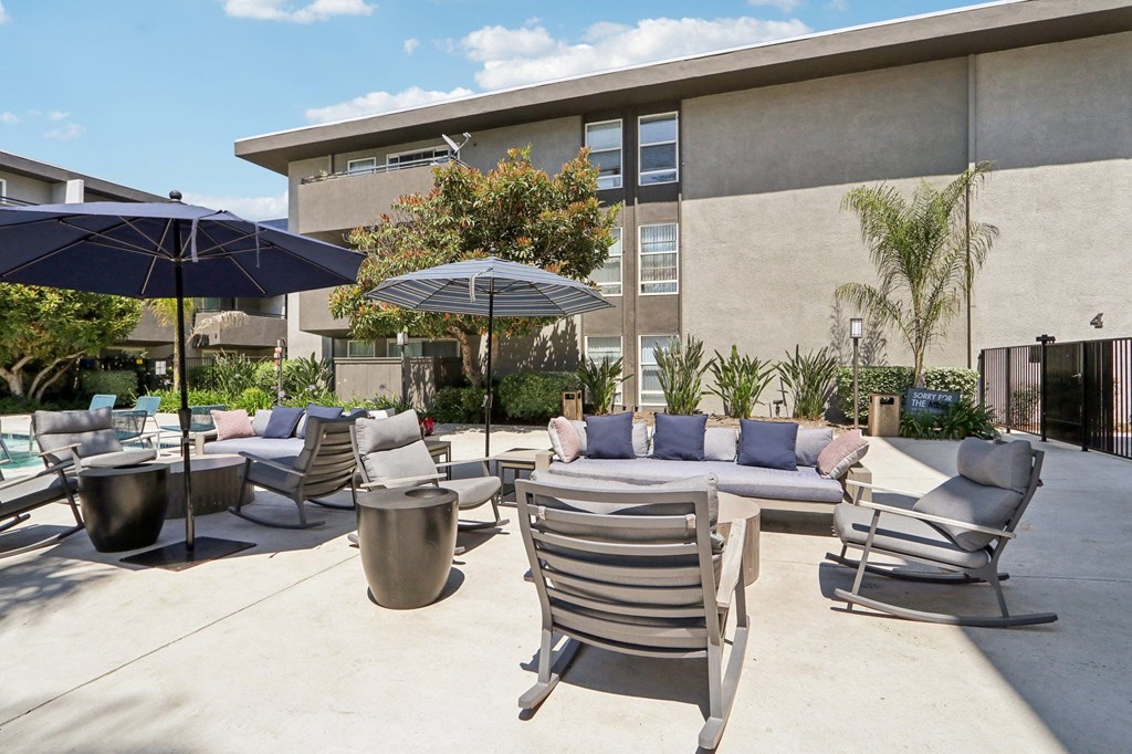 a patio with chairs and tables and umbrellas in front of a building