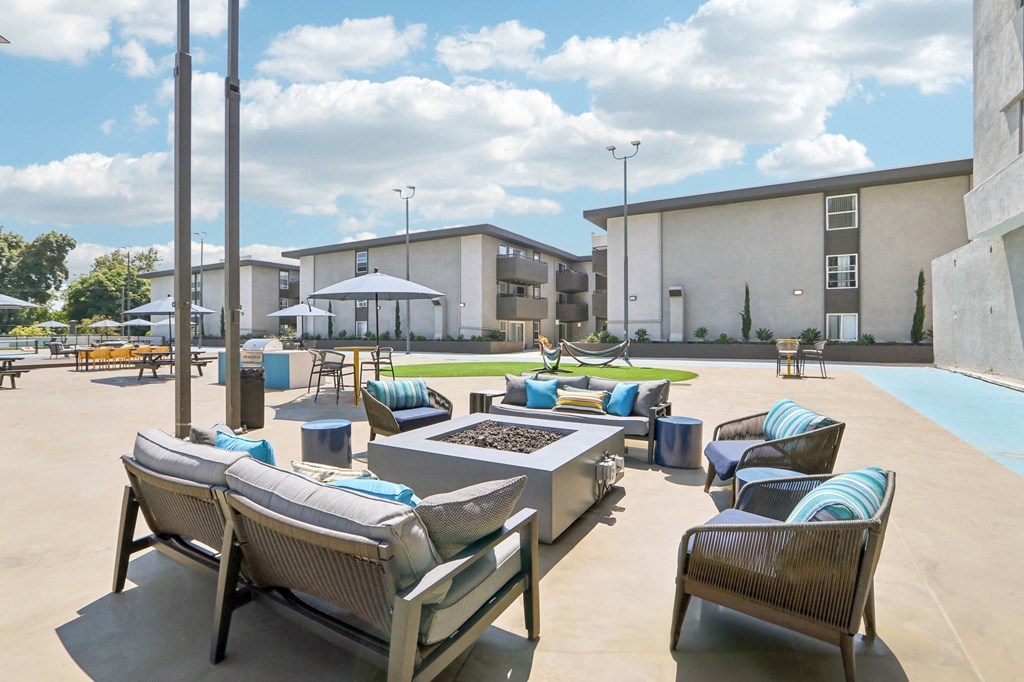 an outdoor lounge area with tables and chairs and a fire pit