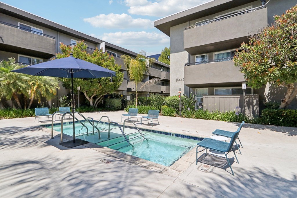 a swimming pool with chairs and an umbrella in front of a building