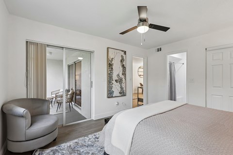 A bedroom with a large bed and a chair.