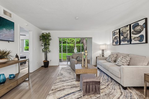 A living room with a couch, a coffee table, and a painting on the wall.