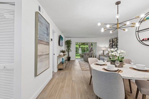 A dining room with a table set for two and a view of the backyard.