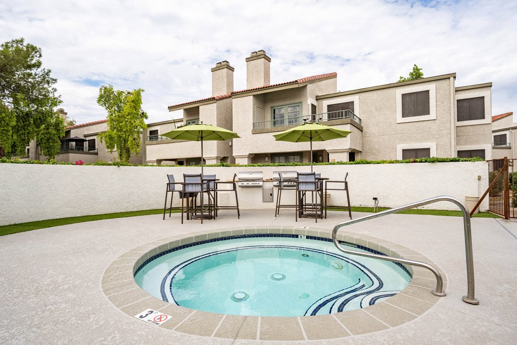 a resort style pool with chairs and umbrellas in front of a house