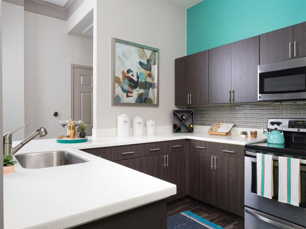 a kitchen with white counter tops and dark cabinets
