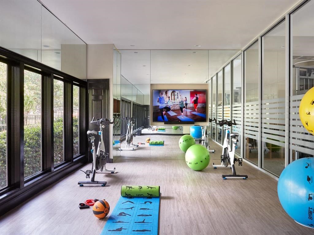 a gym with glass walls and a tv on the wall