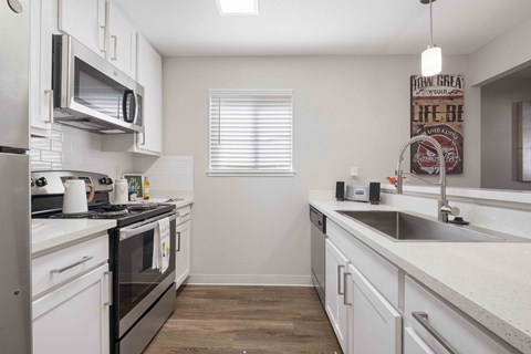 A kitchen with white cabinets and a black stove top oven.
