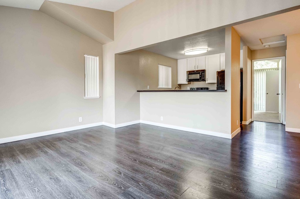 an empty living room and kitchen with wood flooring