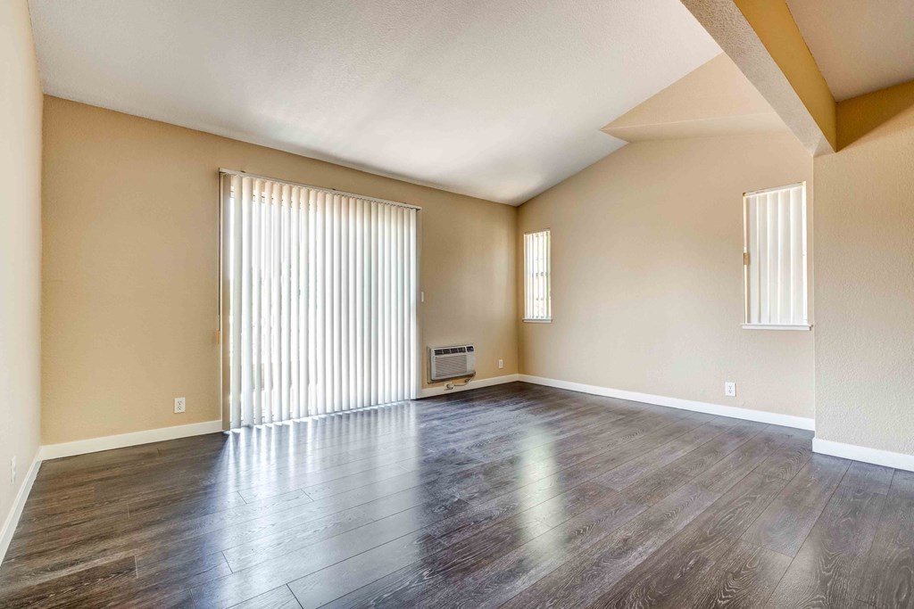 an empty living room with a large window and wood floors