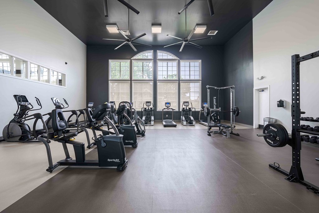 a gym with weights and cardio equipment and a large window