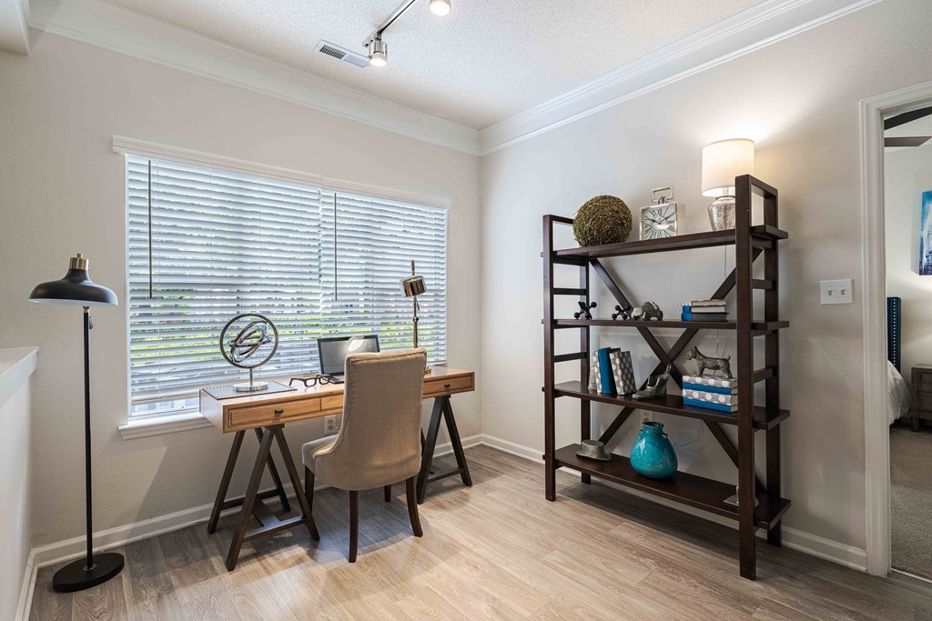 a home office with a large window and a desk with a chair