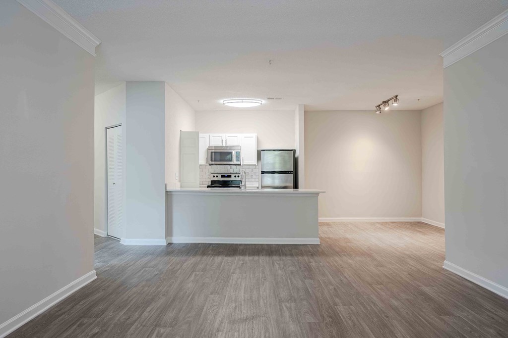 a renovated living room with a kitchen and hard wood flooring